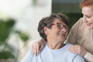 Krankenschwester hält Hand auf Schulter von älterer Frau