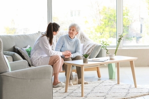 Frau redet mit älterer Dame auf dem Sofa
