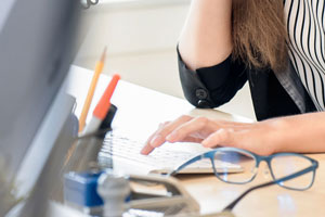 Ausschnitt Schreibtisch - Hand tippt auf Tastatur