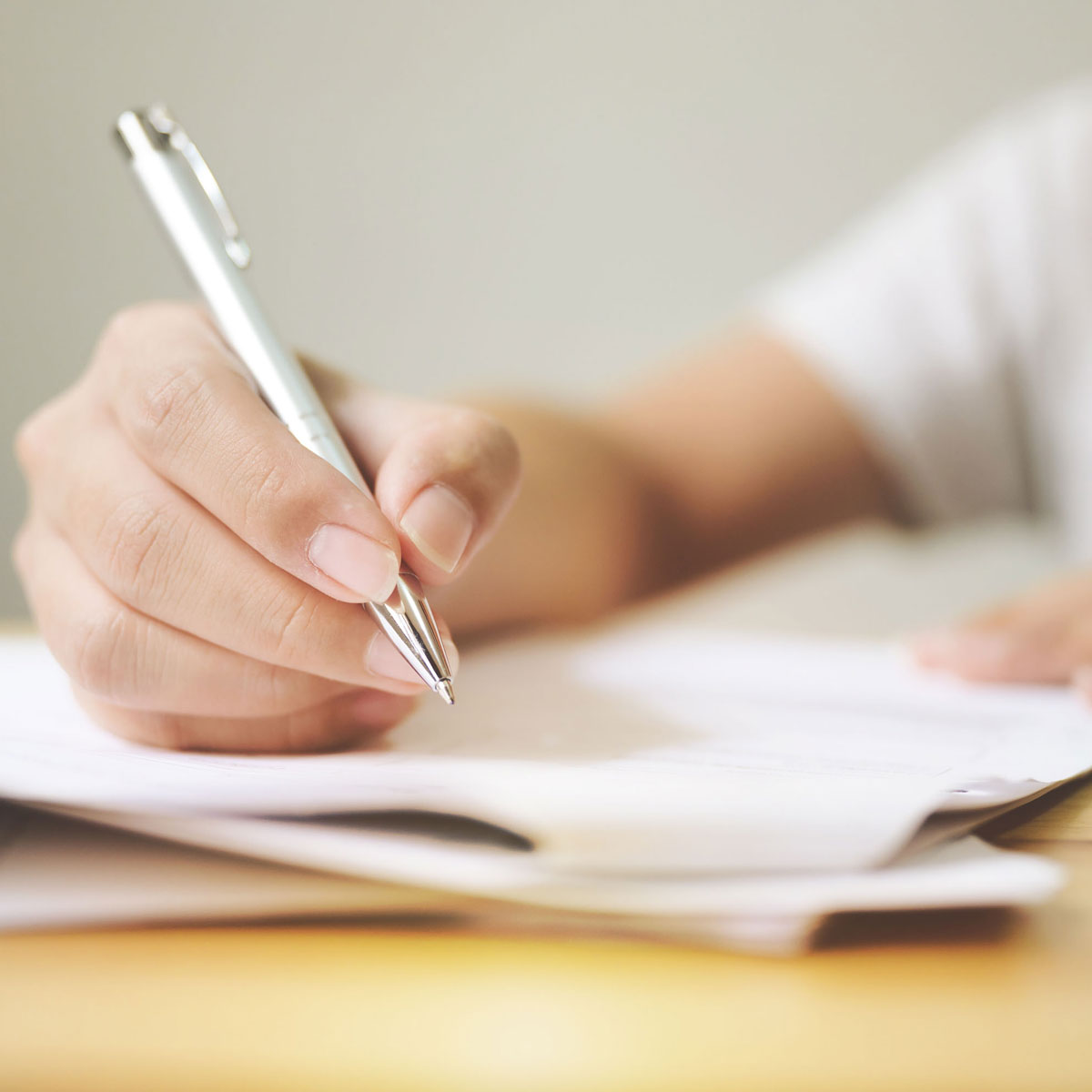 Frau hält Kugelschreiber über ein Blatt Papier